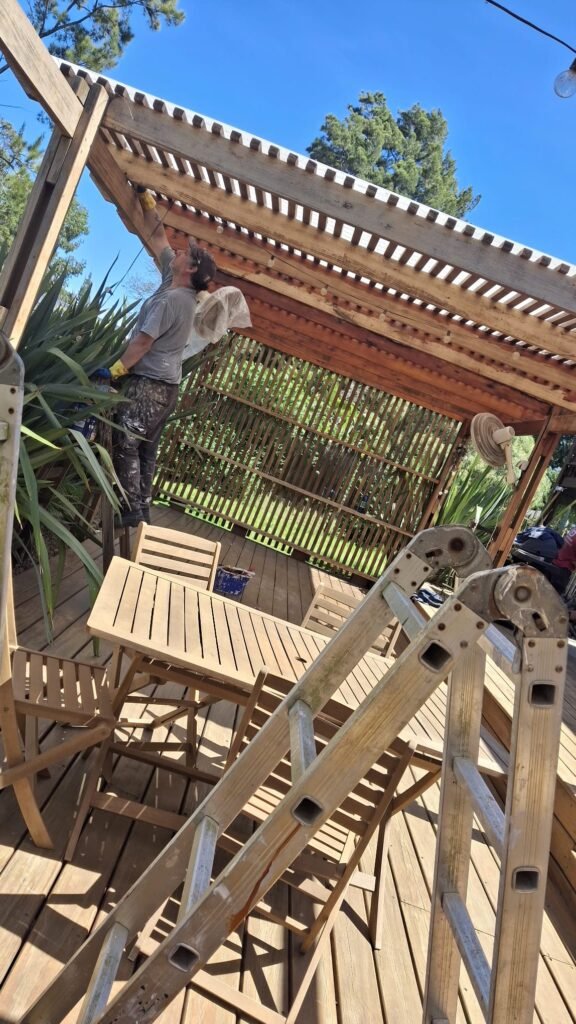 Técnico de Deslindar.com.uy aplicando protector de madera en una pérgola de barbacoa.