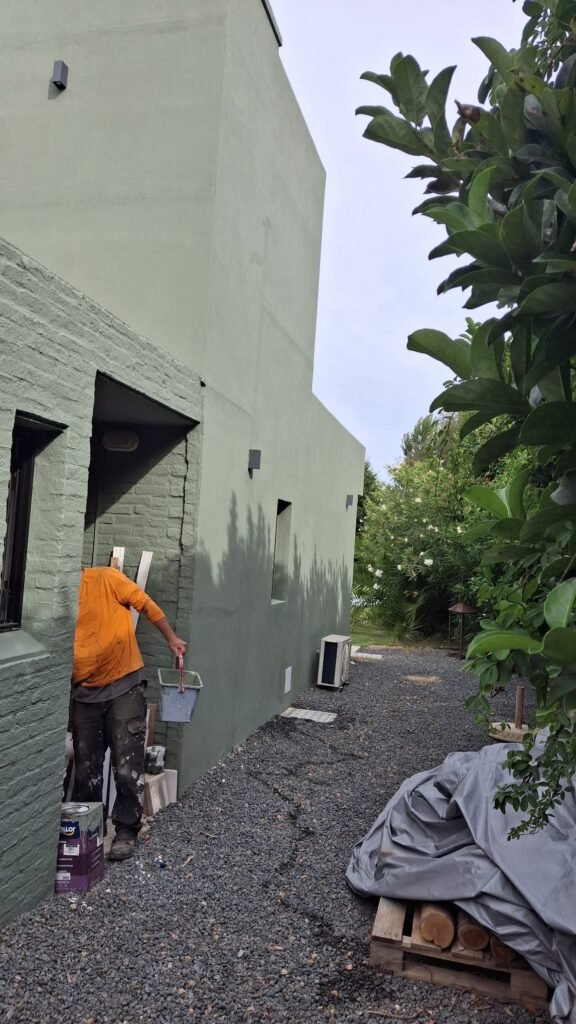 Pared exterior en proceso de pintura gris moderno tras reparación de revoques y limpieza profunda por Deslindar.
